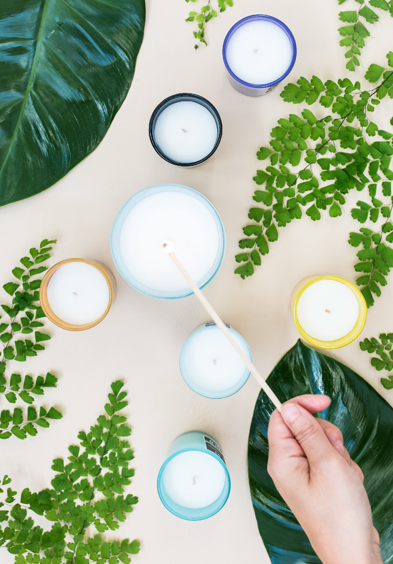 photo of a woman's hand using an object to make candles and insert wicks in them
