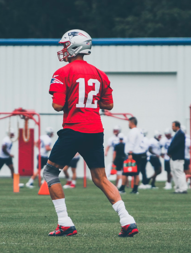 former nfl quarterback tom brady in a number 12 red patriots jersey at practice