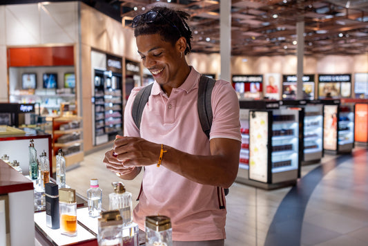 a man in pink shirt samples colognes at airport shop
