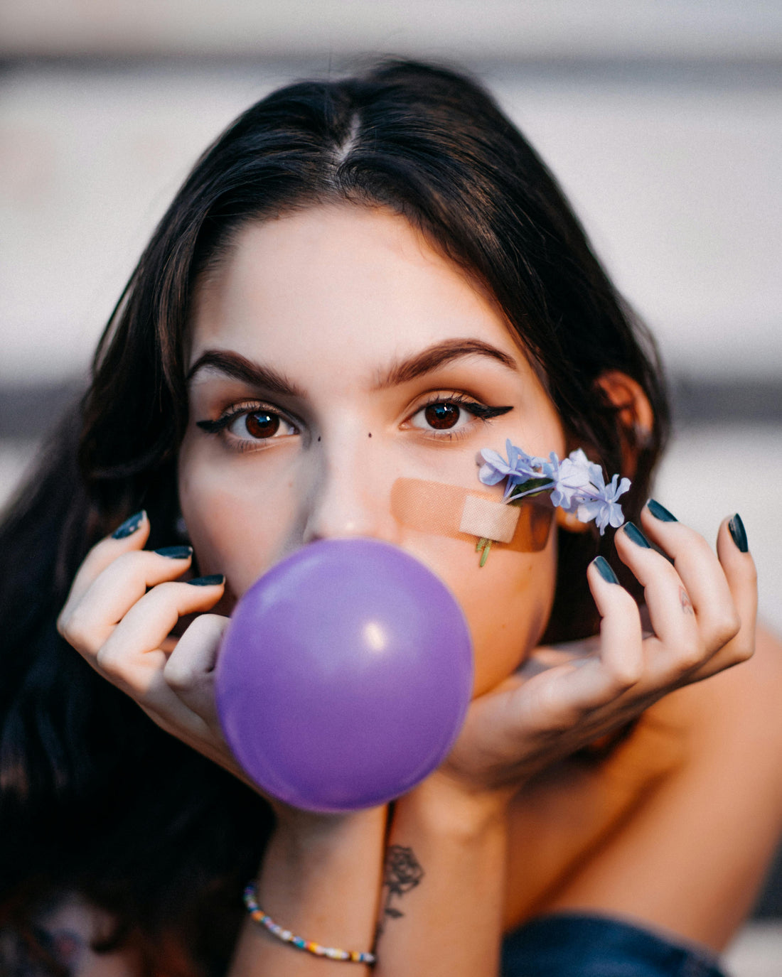 woman blowing a purple grape colored bubblegum