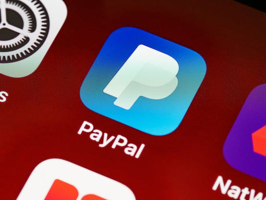 photo of a blue paypal app icon on a mobile screen surrounded by other apps