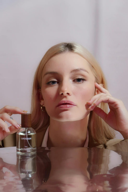 blonde woman with her fingers on a perfume flask