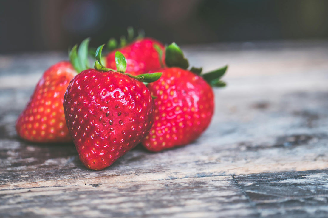 4 strawberries placed on a gray wooden surface