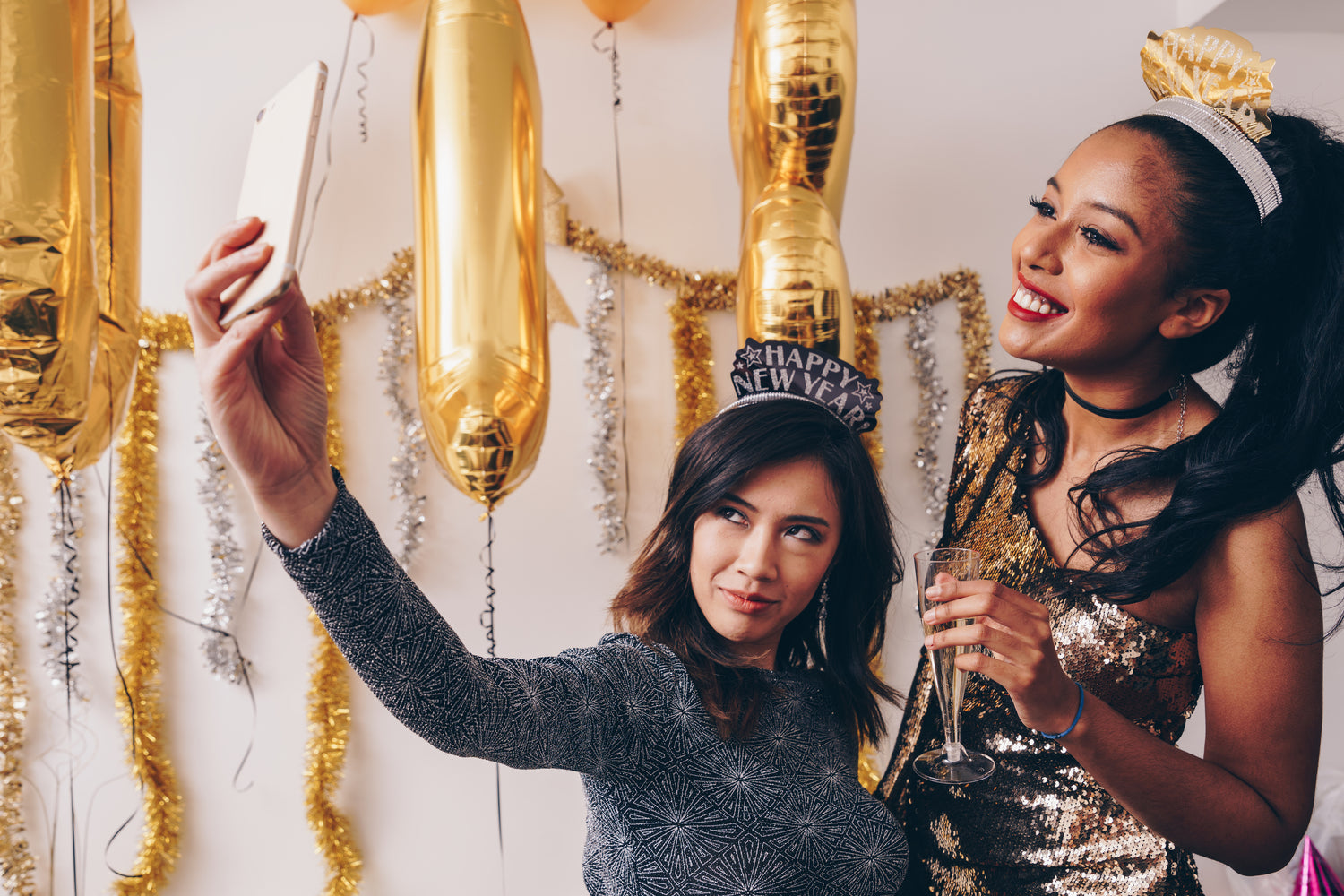 two women smiling at a new year's eve party and taking a selfie