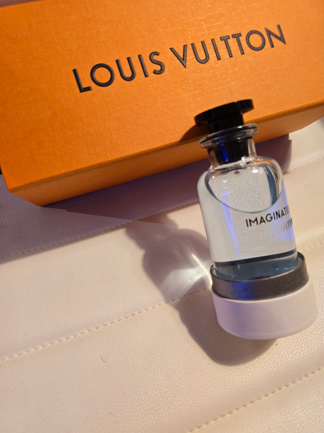 orange louis vuitton package and bottle of imagination cologne