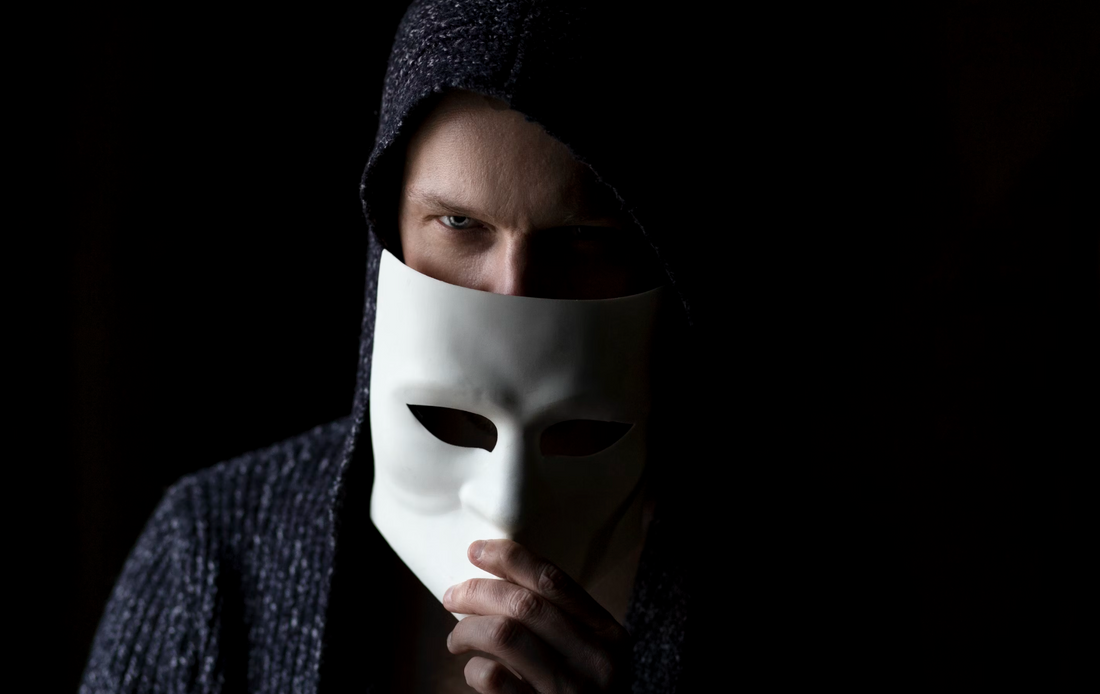 man wearing a hoodie half covering his face with a white mask