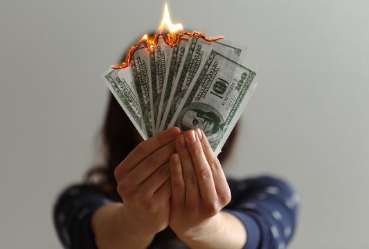 woman holding six one-hundred dollar bills that are each burning at the top