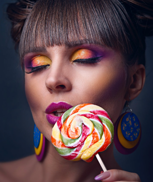 woman holding and tasting a rainbow lollipop 