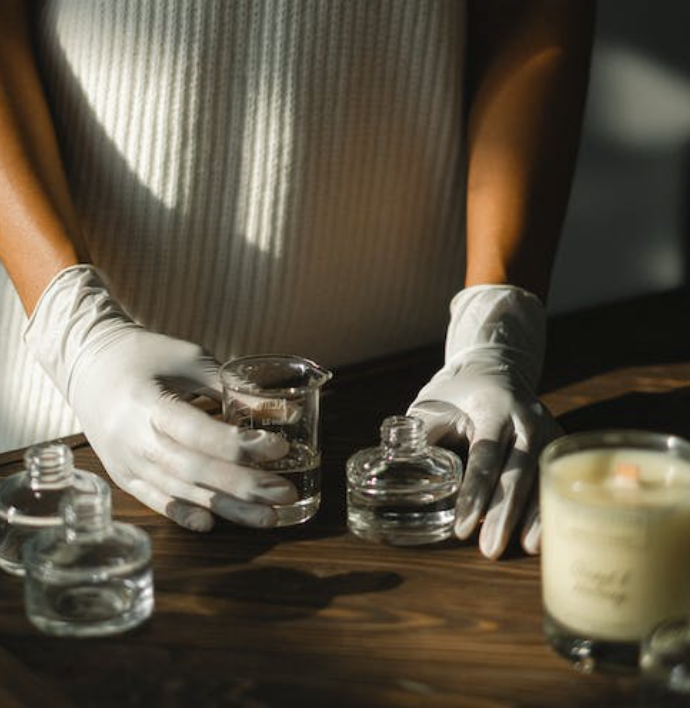 woman wearing latex gloves holding small glass containers preparing her own fragrances