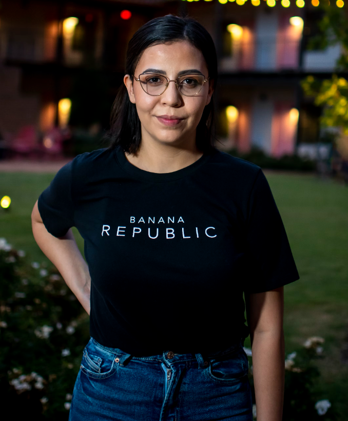 woman standing outside in the evening wearing a black shirt that says banana republic