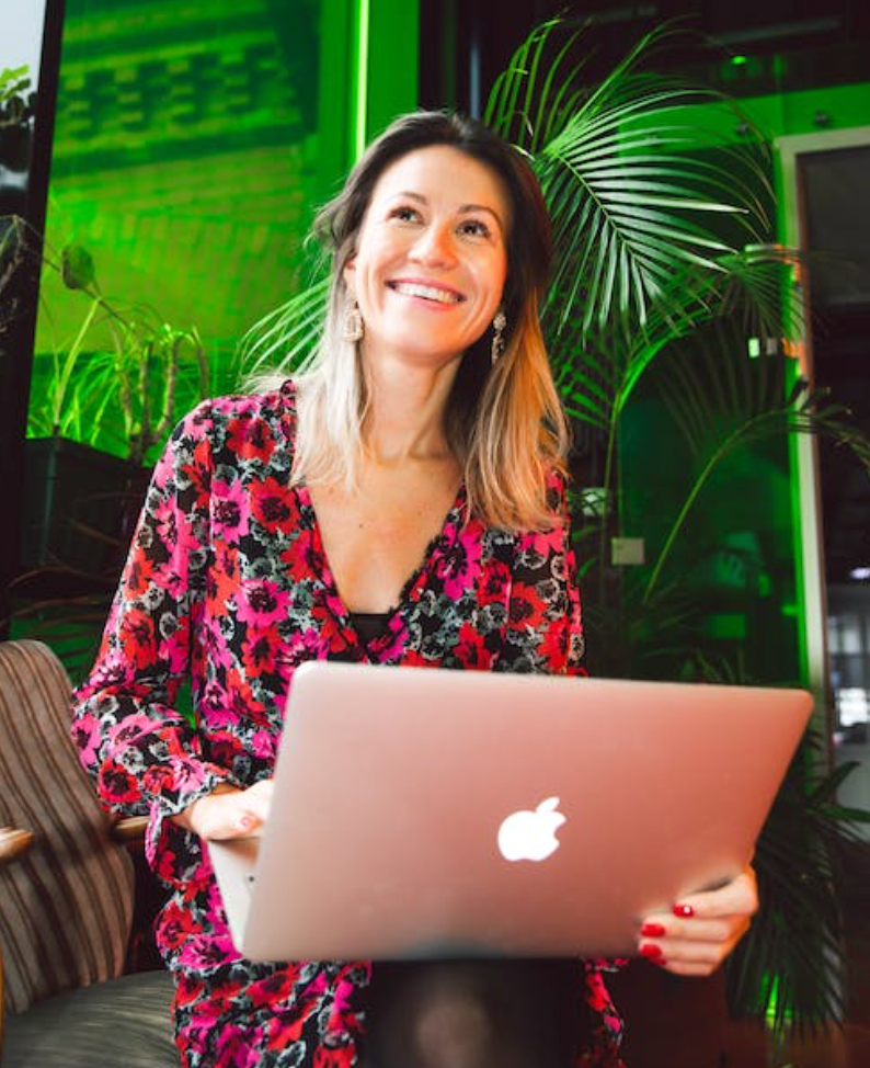 blonde woman with an apple macbook on her lap laughing at a perfume joke