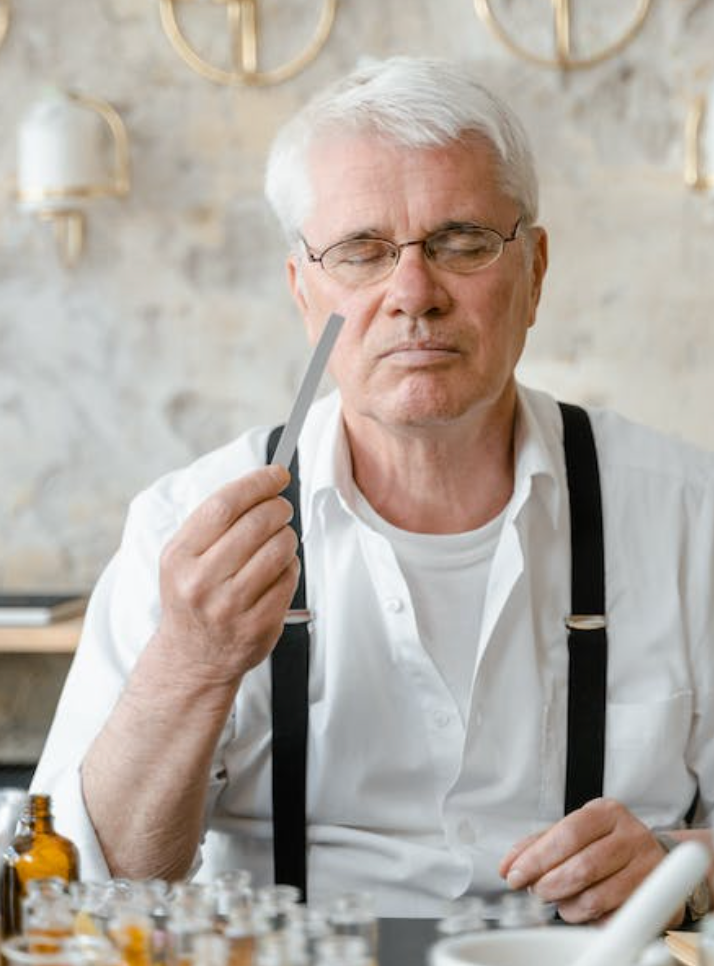 male perfume maker smelling a fragrance on a test strip