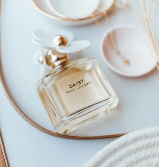 bottle of daisy perfume with a white flower cap by marc jacobs