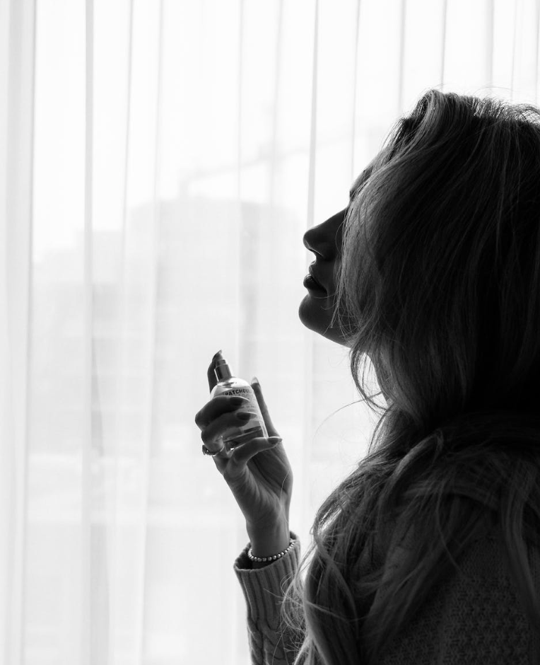 black and white photo of a woman preparing to apply perfume