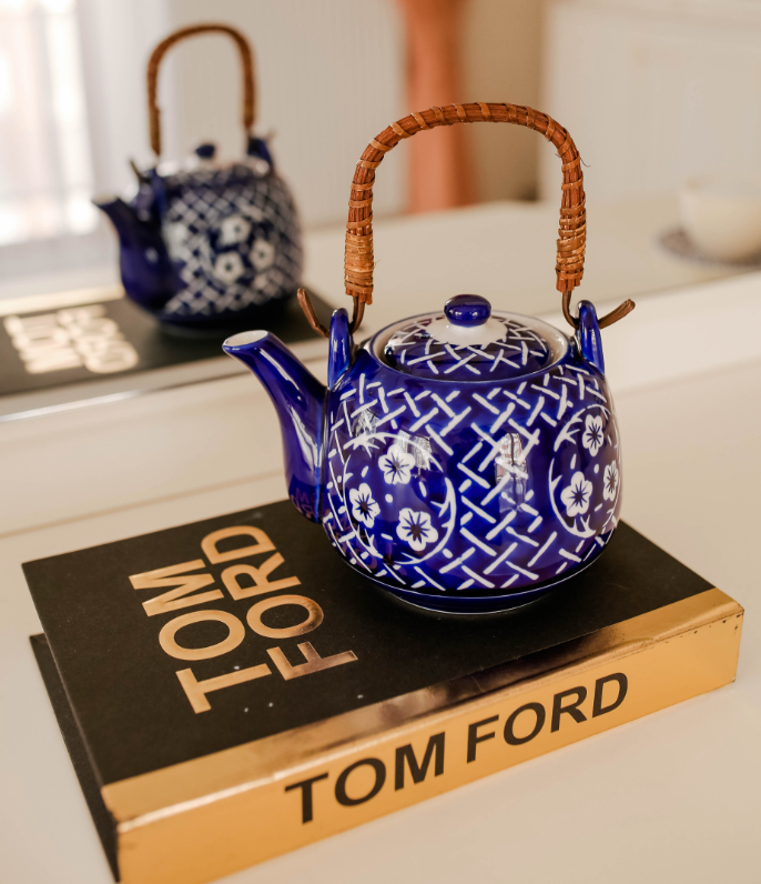 a brown and gold colored Tom Ford book with a blue and white kettle on top of it