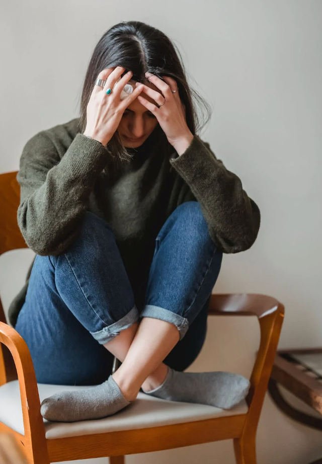 stressed woman with her hands on her head sitting on a chair