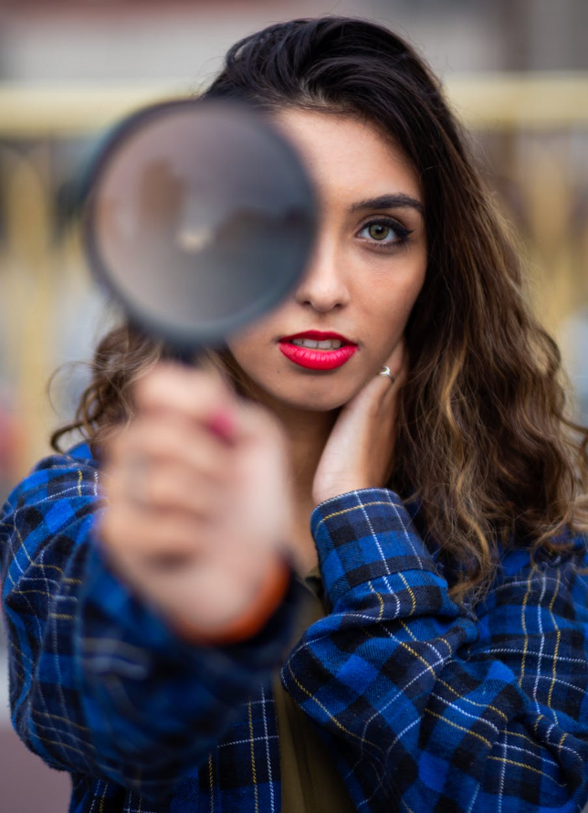 woman holding a magnifying glass looking hard to find something