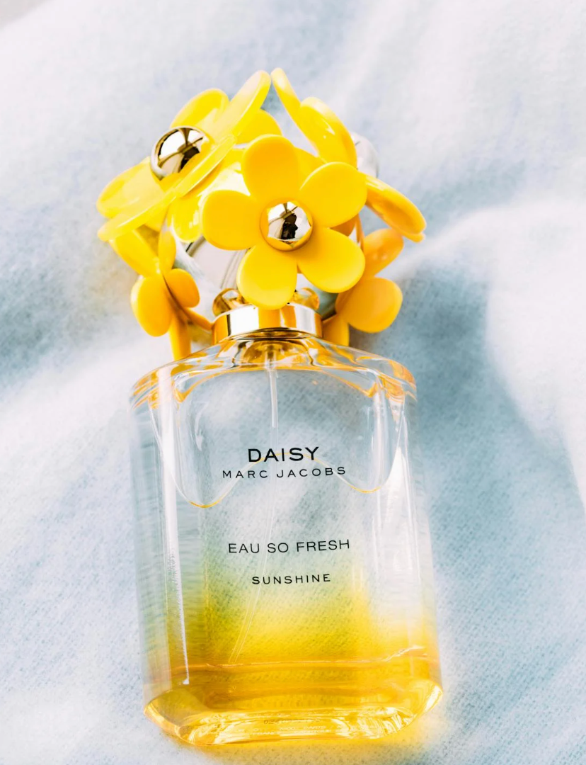 bottle of daisy eau so fresh perfume by marc jacobs laying on a soft surface
