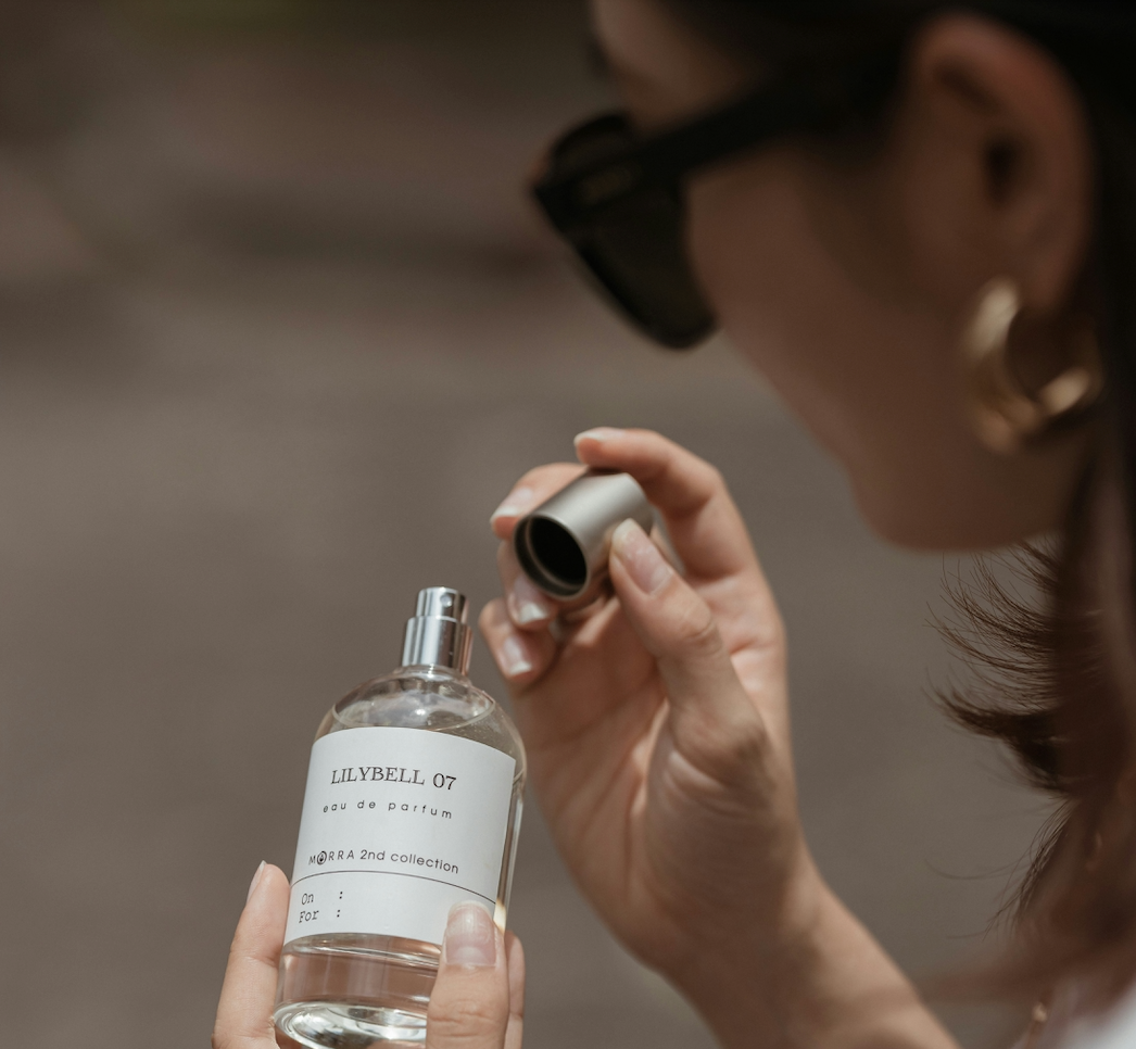 woman in dark sunglasses holding a bottle of lillybell 07 perfume