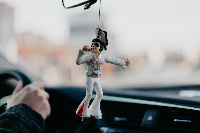 elvis figurine hanging in a car's rear-view mirror panel