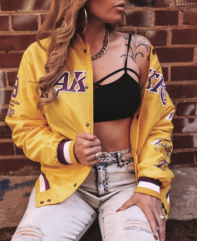 woman wearing a purple and gold lakers jersey along with jeans and a black top