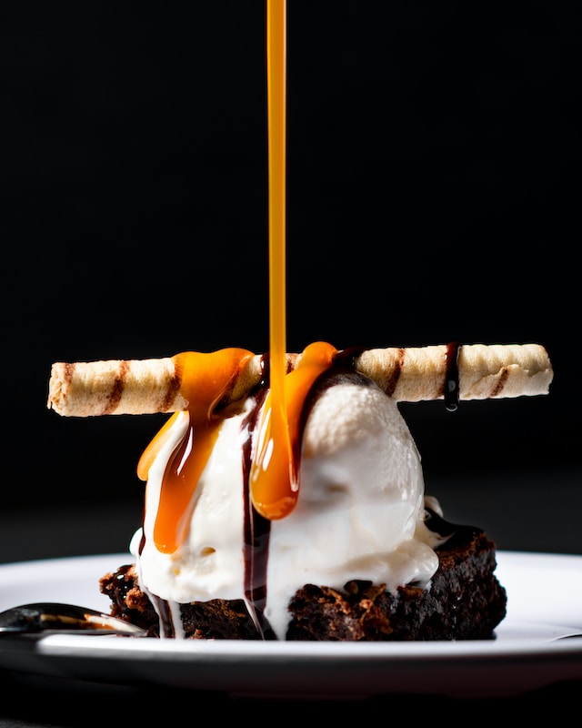 caramel being drizzled onto a scoop of vanilla ice cream