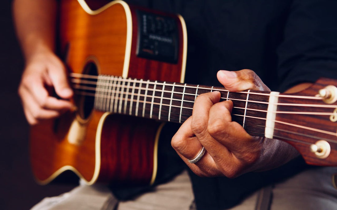 man holding and playing a brown guitar