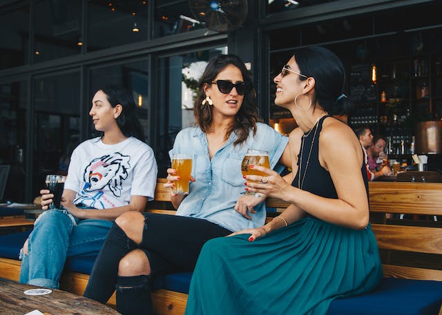 three women holding drinks after work