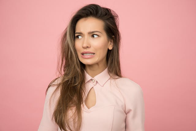 woman in a pink top with a slightly confused look