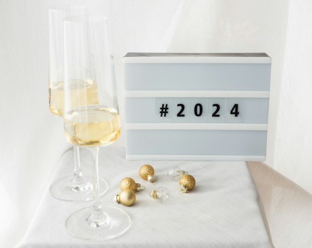 2 champagne glasses next to a sign that reads #2024