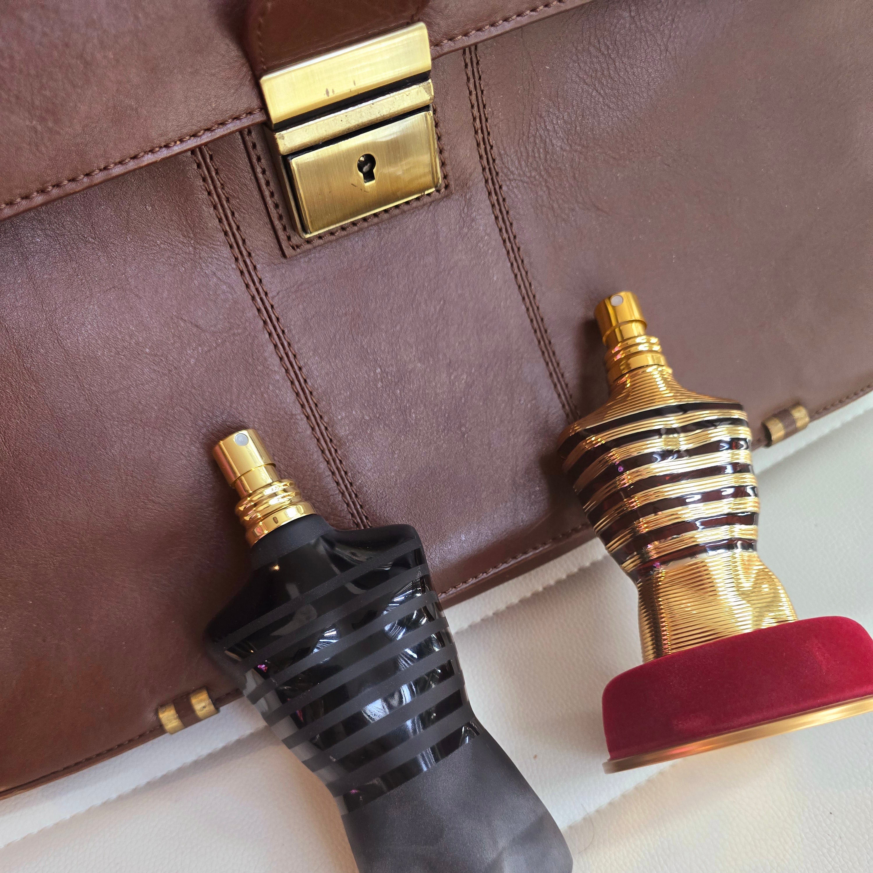 bottle of jean paul gaultier's le male le parfum and le male elixir in front of brown briefcase